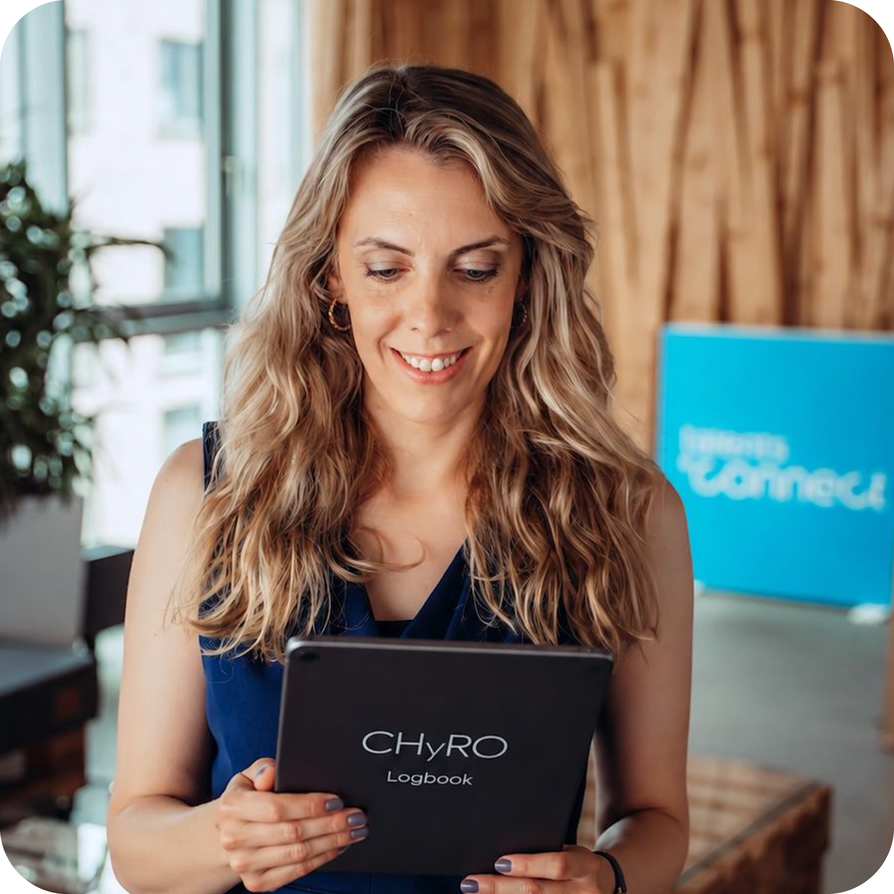 Samira Helbig, Chief Hybrid Resources Officer at talentsconnect, smiles while reading a tablet marked “CHyRO Logbook” in the talentsconnect office.